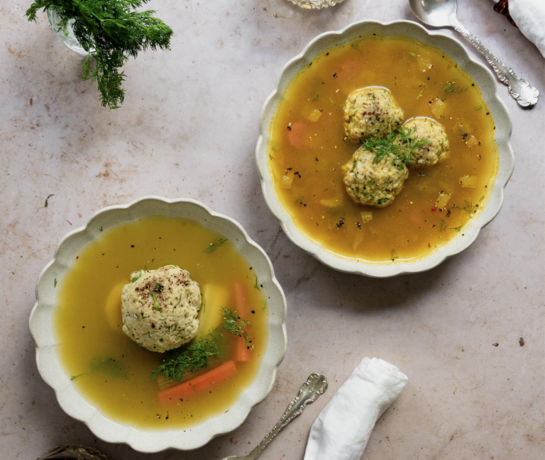 two bowls of matzo ball soup on a grey background